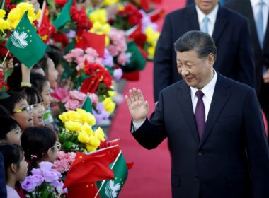 Chinese President Xi Jinping waves at children holding Chinese and Macau flags after arriving at Macau International Airport in Macau